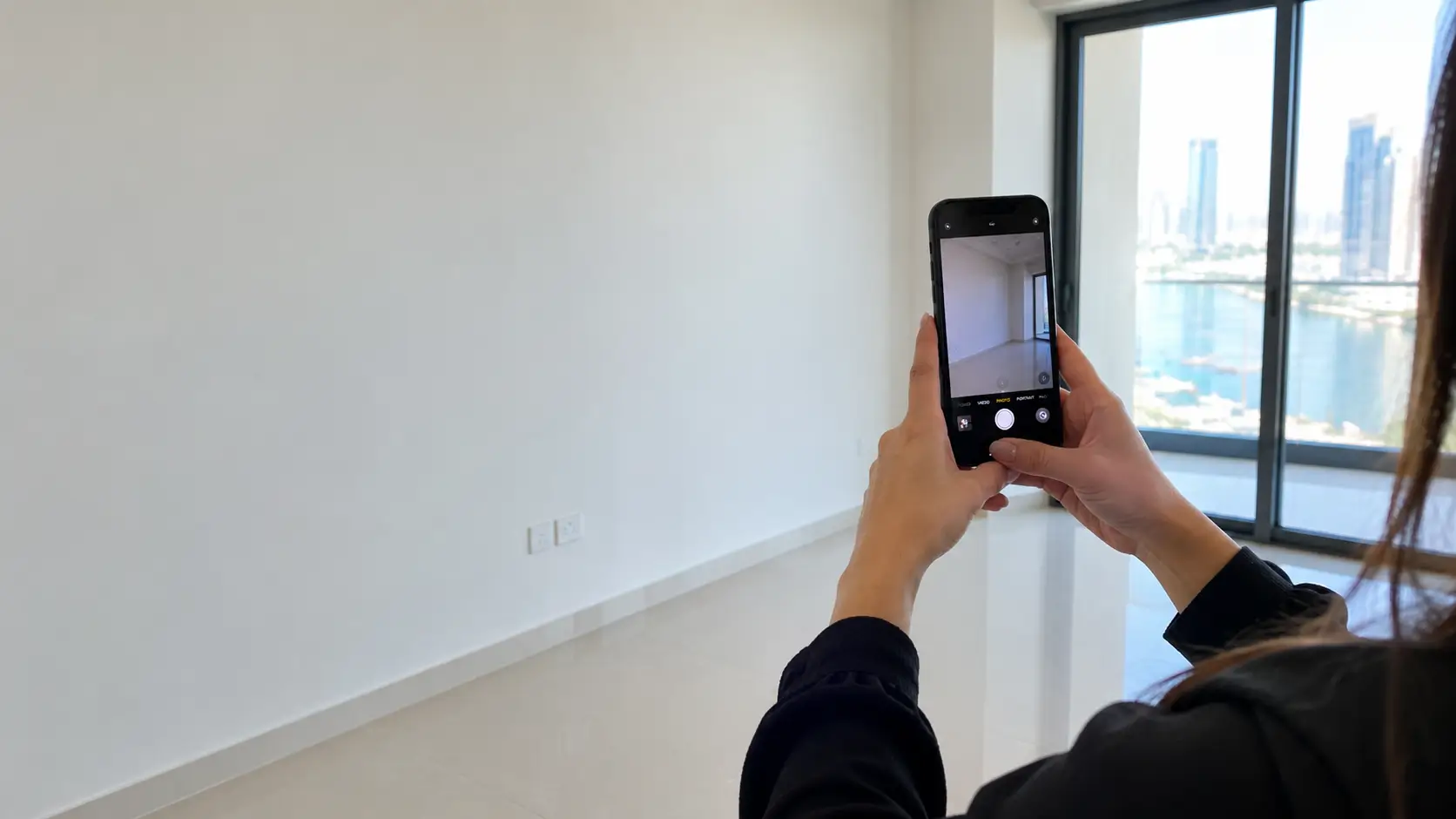 Tenant photographing walls during a move-out inspection in Dubai