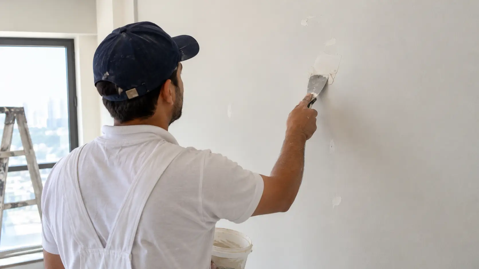 Painter filling cracks in a wall before repainting